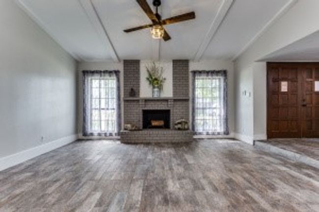 Unfurnished living room with lofted ceiling with beams, a fireplace, a ceiling fan, and plenty of natural light | Image 7