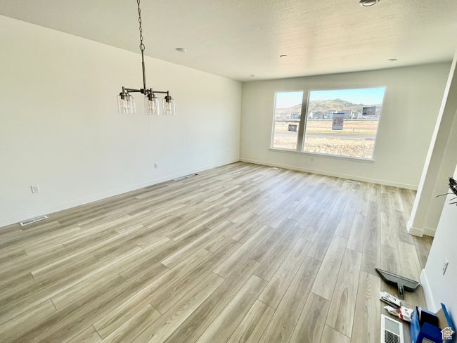 Unfurnished dining area featuring a chandelier and light wood-style floors | Image 7