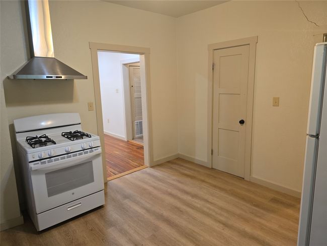 Kitchen featuring white appliances, wall chimney range hood, and light wood finished floors | Image 6