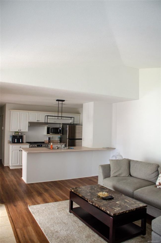 Kitchen featuring appliances with stainless steel finishes, under cabinet range hood, dark wood-style floors, and a sink. Virtual Staging | Image 12