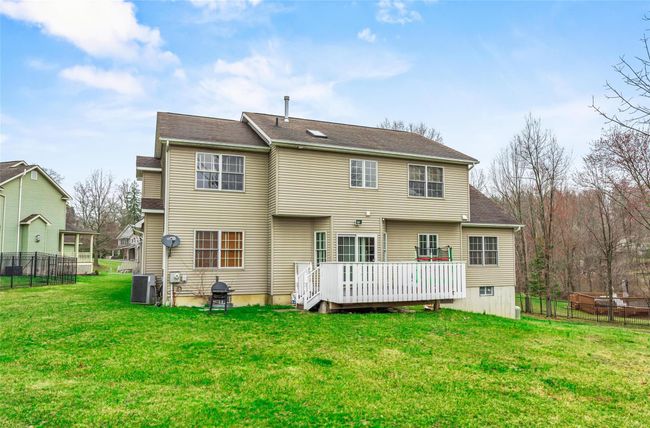 Rear view of property with fence, a wooden deck, a lawn, and central air condition unit | Image 46