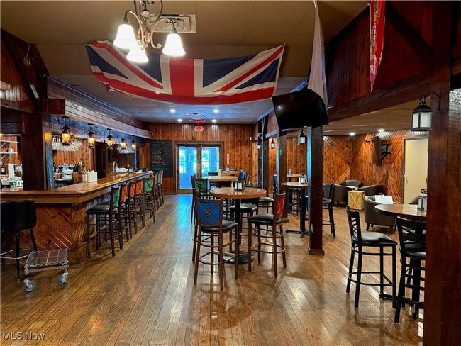 Dining space featuring wooden walls, hardwood / wood-style floors, a community bar, and a chandelier | Image 14