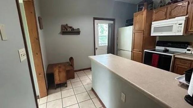 Kitchen featuring light tile patterned flooring and white appliances | Image 11