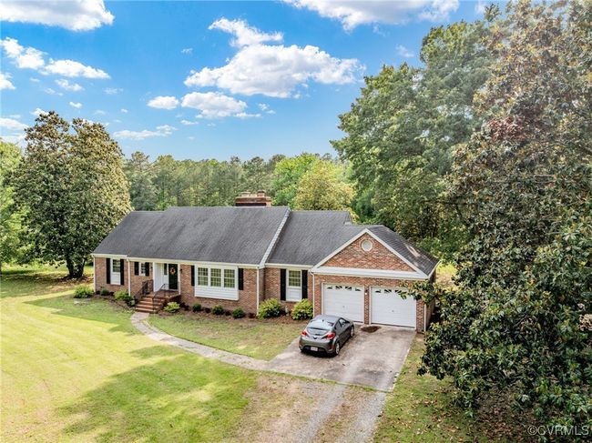 View of front of home featuring dirt driveway, an attached garage, brick siding, a front lawn, and a chimney | Image 45