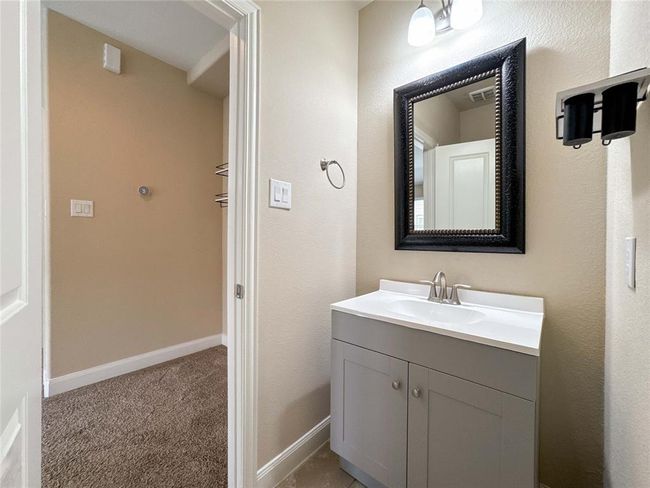 This photo shows a compact bathroom with a modern vanity featuring a white countertop and a sleek faucet. It has a large, decorative framed mirror and neutral wall colors, providing a clean and inviting atmosphere. | Image 42