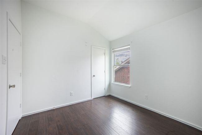 Unfurnished bedroom featuring dark wood-style floors, baseboards, and vaulted ceiling | Image 12