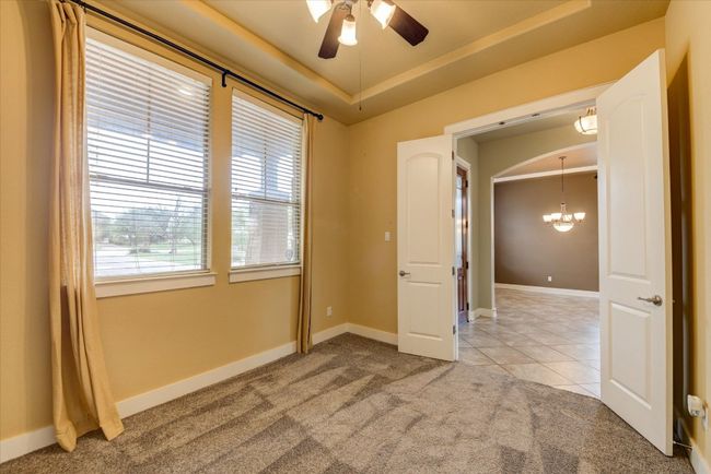 Study with light tile patterned flooring, a raised ceiling, light carpet, and ceiling fan | Image 7
