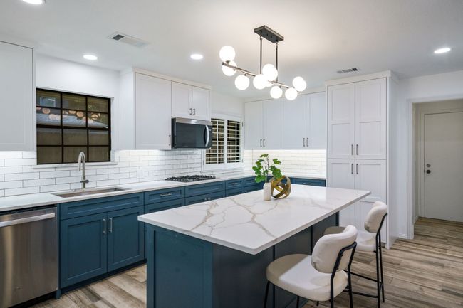 Kitchen with blue cabinets, appliances with stainless steel finishes, recessed lighting, light wood-type flooring, and a breakfast bar area | Image 14