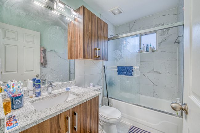 Full bathroom featuring vanity, enclosed tub / shower combo, and tile walls | Image 20