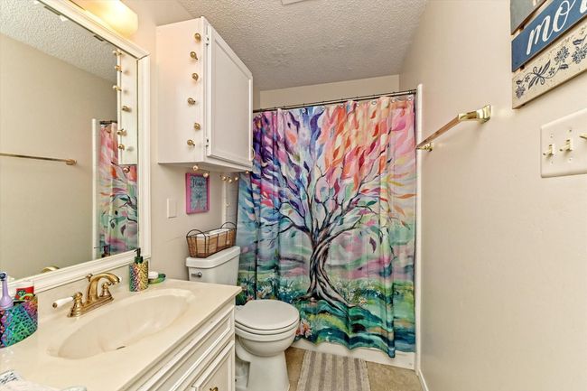 Bathroom featuring curtained shower, toilet, vanity, and a textured ceiling | Image 18