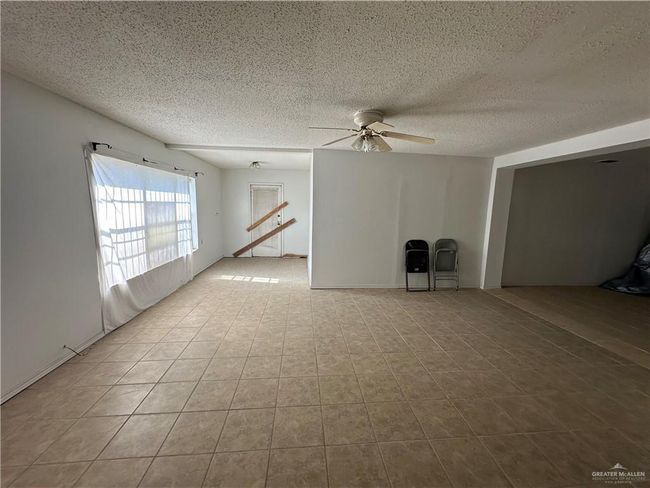 Unfurnished living room featuring a textured ceiling and ceiling fan | Image 7