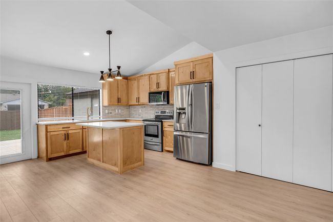 Kitchen with stainless steel appliances, light wood-style flooring, light countertops, backsplash, and lofted ceiling | Image 14