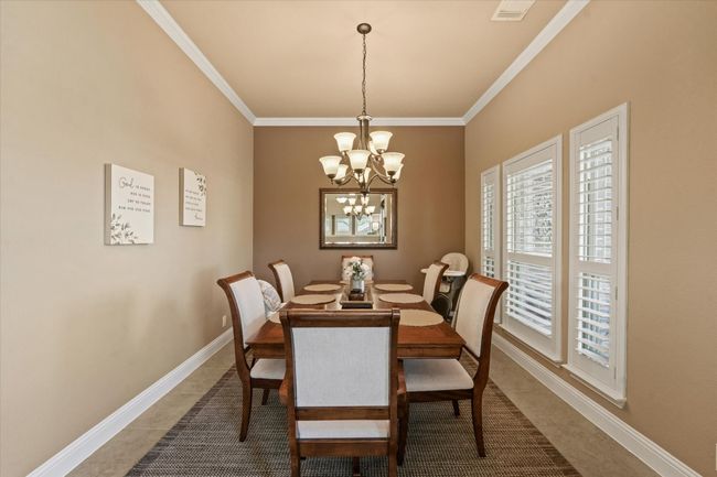 Dining room with a notable chandelier, baseboards, crown molding, and visible vents | Image 7