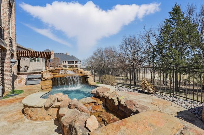 The spa has a waterfall feature and flows into the pool. | Image 35