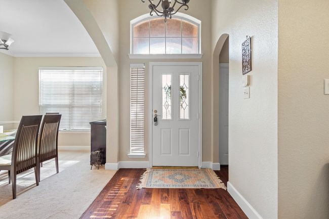 Foyer featuring arched walkways, a chandelier, wood-type flooring, and crown molding | Image 6