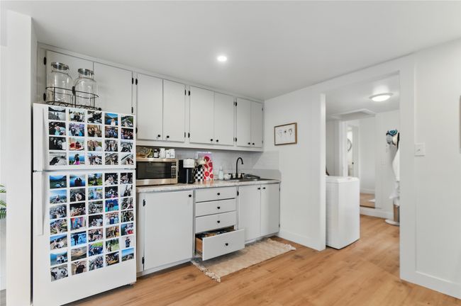 Kitchen featuring white cabinets, light countertops, stainless steel microwave, freestanding refrigerator, and light wood-type flooring | Image 27