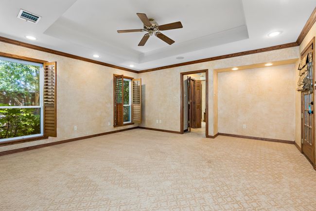 Master suite featuring crown molding, a raised ceiling, recessed lighting, and ceiling fan | Image 11