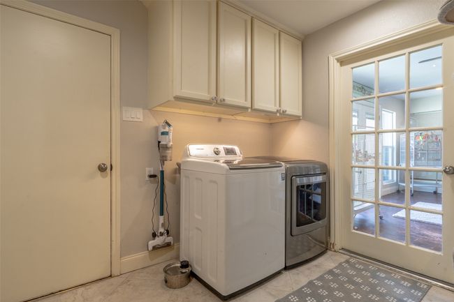 Laundry room featuring cabinet space, washing machine and clothes dryer, light tile patterned floors, and baseboards | Image 25