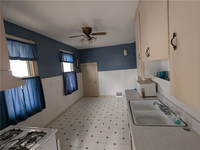 First-Floor Kitchen with white cabinetry, white appliances, sink, and ceiling fan | Image 11