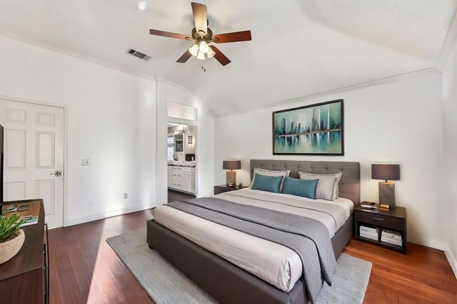 Bedroom with vaulted ceiling, wood finished floors, baseboards, connected bathroom, and ceiling fan | Image 16