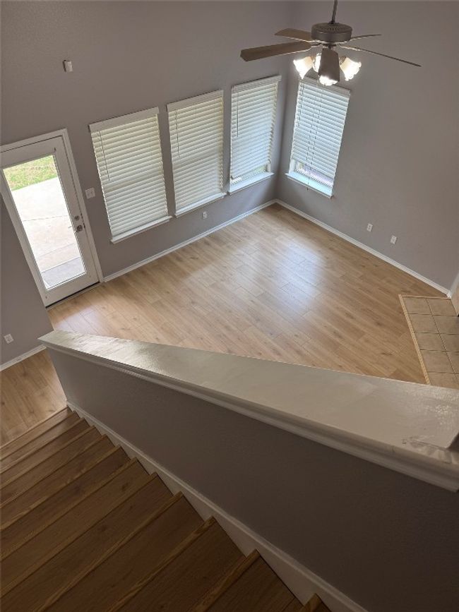 Stairs with wood finished floors, a ceiling fan, and baseboards | Image 25