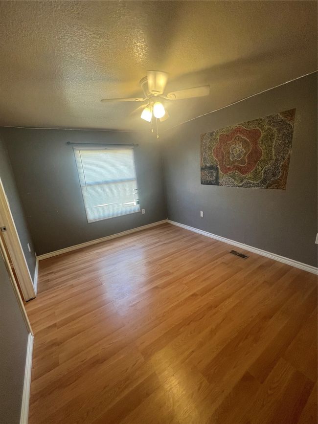 Spare room with a textured ceiling, wood finished floors, and a ceiling fan | Image 10