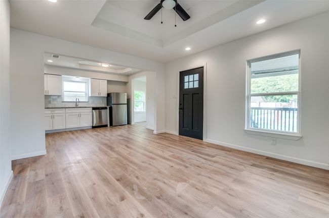 Entrance foyer featuring a ceiling fan, light wood-type flooring, a tray ceiling, baseboards, and visible vents | Image 7