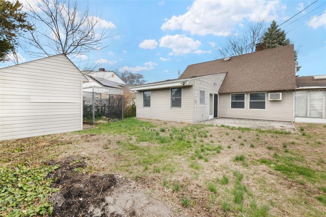 Back of house featuring a chimney, a wall unit AC, fence, a shingled roof, and a patio area | Image 22