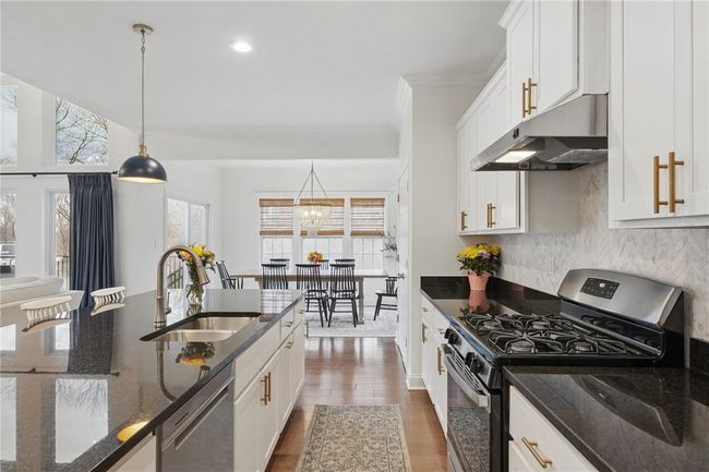 Gourmet kitchen seamlessly connected to the great room, featuring white cabinetry, granite countertops, stainless steel appliances, and a spacious island with pendant lighting. Open-concept layout provides a perfect flow for entertaining and everyday living. | Image 15