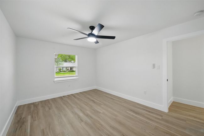 Empty room with light wood finished floors, a ceiling fan, baseboards, and a smoke detector | Image 25