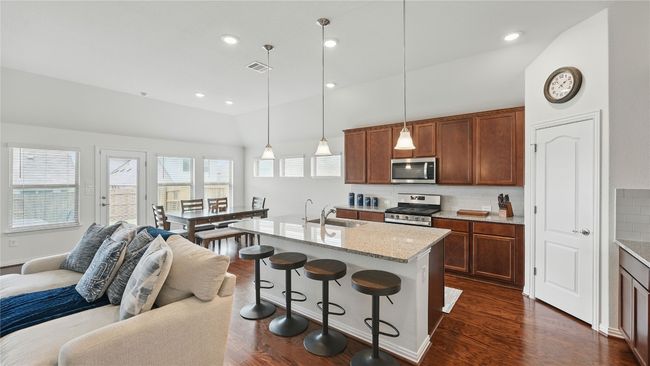 Kitchen with appliances with stainless steel finishes, lofted ceiling, open floor plan, backsplash, and a breakfast bar area | Image 19