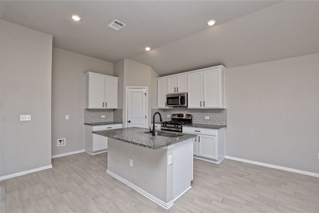 Kitchen featuring visible vents, a center island with sink, light wood-style flooring, appliances with stainless steel finishes, and a sink | Image 10