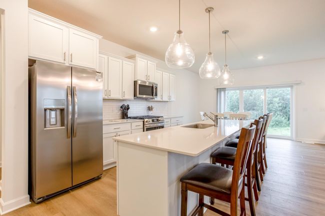 Sleek and functional, this kitchen offers abundant cabinetry, tile backsplash, and a spacious layout ideal for everyday living and entertaining. | Image 6