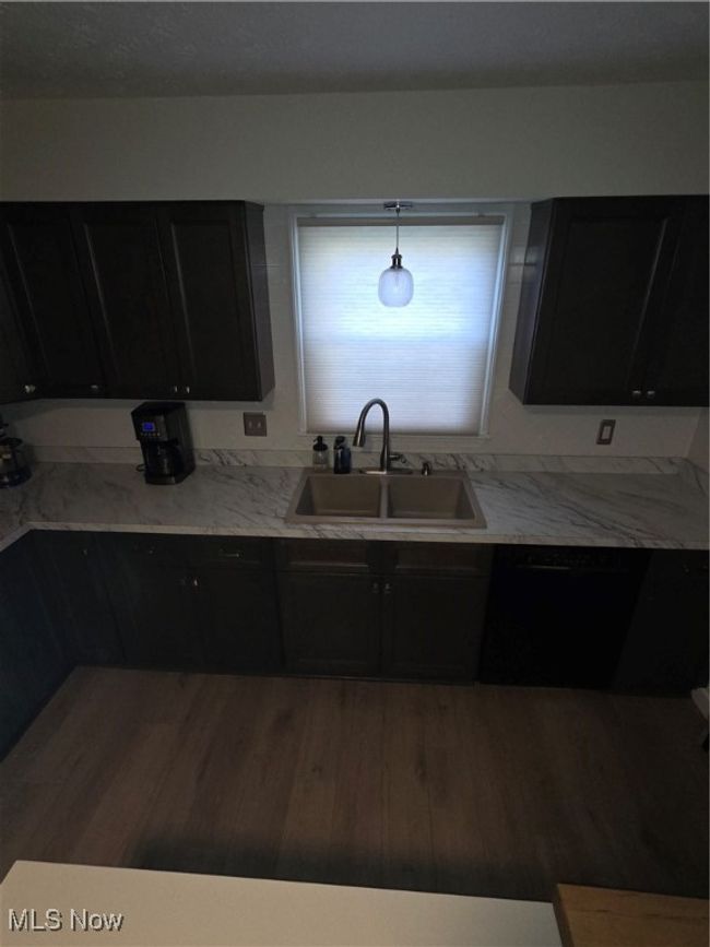 Kitchen featuring a sink, dishwashing machine, dark cabinets, wood finished floors, and light stone countertops | Image 9