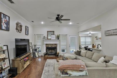 Living room featuring crown molding, dark wood-type flooring, ceiling fan, and a fireplace | Image 3