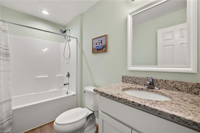 Bathroom with toilet, shower / tub combo, vanity, and wood finished floors | Image 19