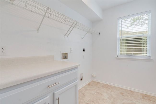 The upstairs laundry room is spacious and well-equipped with cabinetry for storage, a wire rack for hanging clothes, and washer/dryer connections. | Image 20
