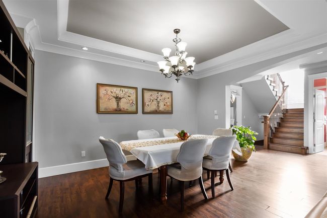 Dining room featuring a tray ceiling, a chandelier, stairway, recessed lighting, and wood finished floors | Image 8
