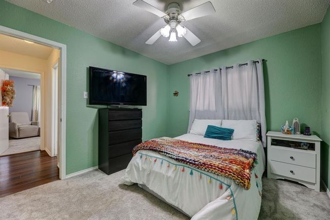 Carpeted bedroom featuring a textured ceiling, a ceiling fan, and baseboards | Image 9
