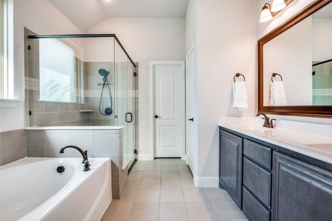 Bathroom with a bath, a shower stall, tile patterned flooring, double vanity, and lofted ceiling | Image 19