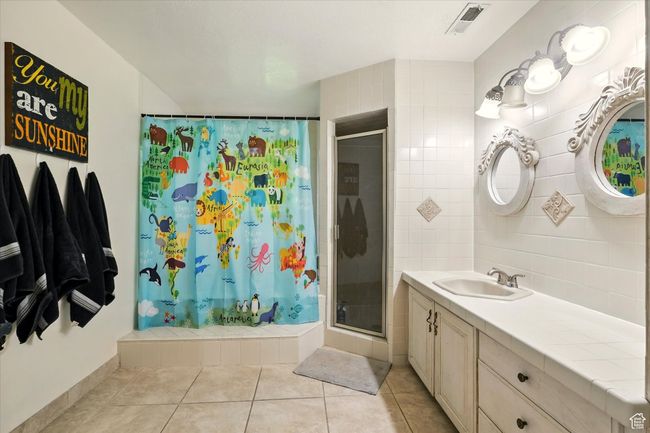 Bathroom with a stall shower, vanity, and tile patterned flooring | Image 39