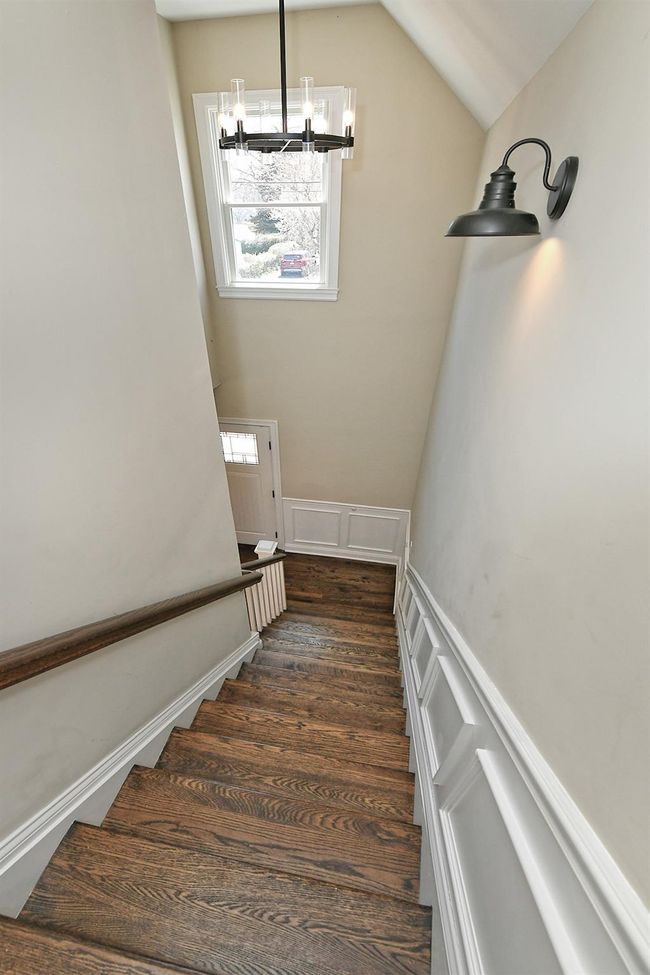 Stairs featuring a wainscoted wall, vaulted ceiling, a chandelier, wood finished floors, and a decorative wall | Image 35