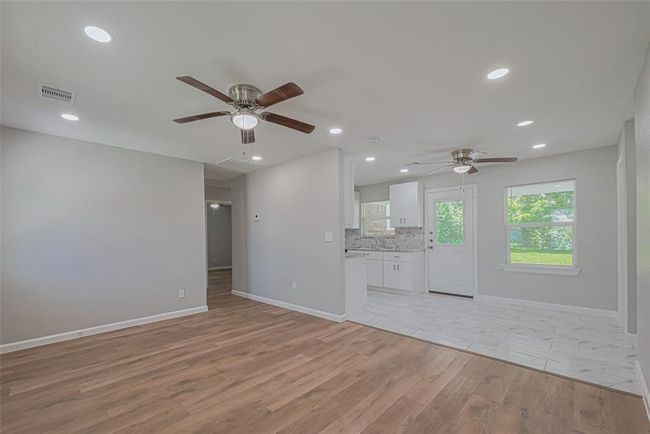 Enjoy a natural transition from the living room to the dining area, with a half wall partially separating the kitchen for visual interest and openness. | Image 8