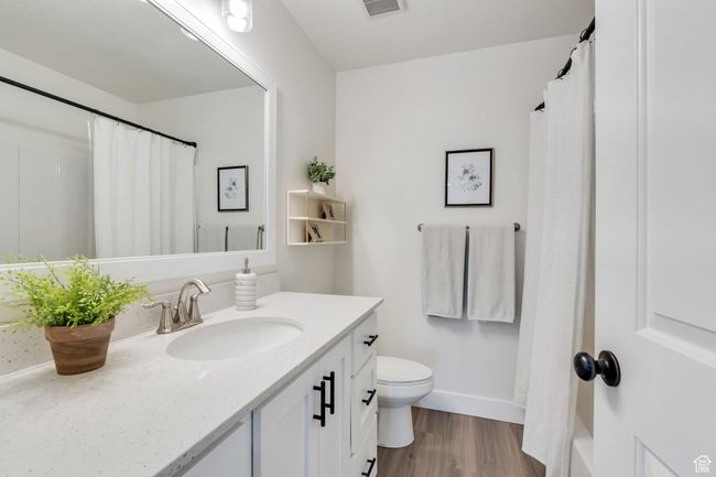 Full bathroom featuring vanity, baseboards, toilet, visible vents, and wood finished floors | Image 19