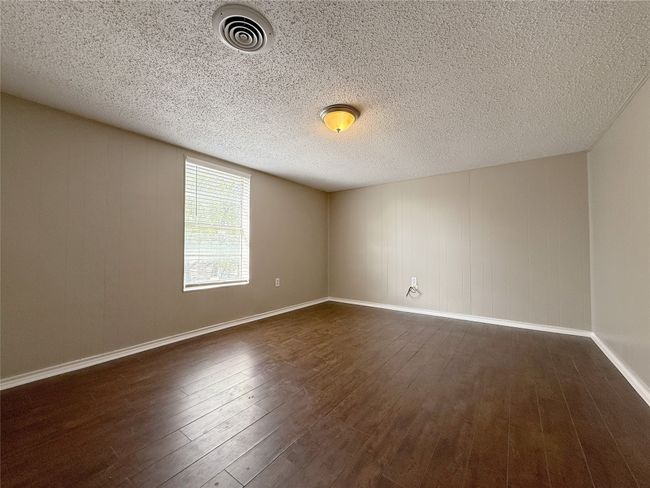 Unfurnished room with dark wood finished floors, a textured ceiling, baseboards, and visible vents | Image 14