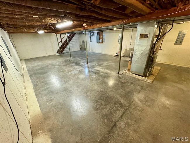 Unfinished below grade area with stairs, heating unit, and electric panel | Image 30
