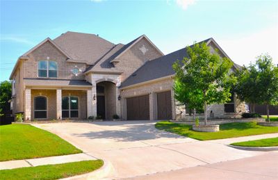 View of front of property featuring stone flowerbed, extended front patio with sitting area, quiet wood garage door | Image 1