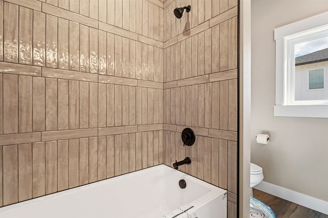 Bathroom with toilet, baseboards, wood finished floors, and tub / shower combination | Image 46