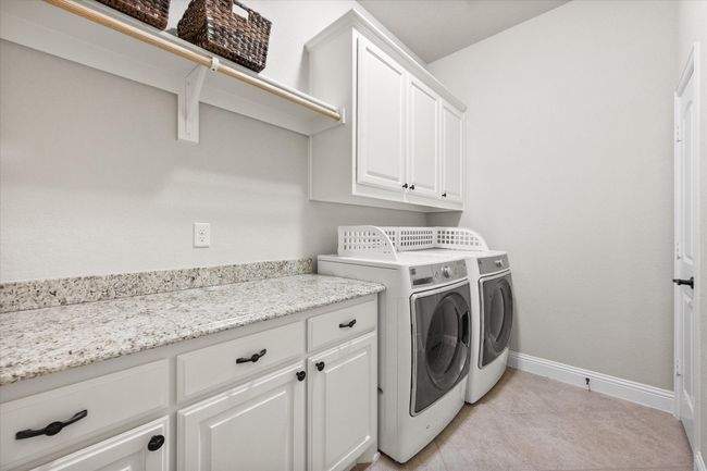 Laundry room featuring cabinet space, independent washer and dryer hookups, and light tile floors | Image 13