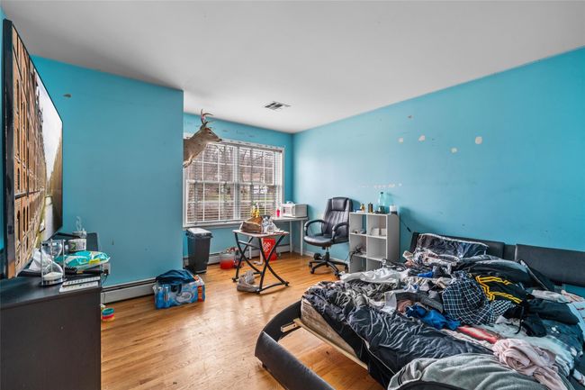 Bedroom featuring a baseboard radiator, visible vents, a baseboard heating unit, and wood finished floors | Image 35